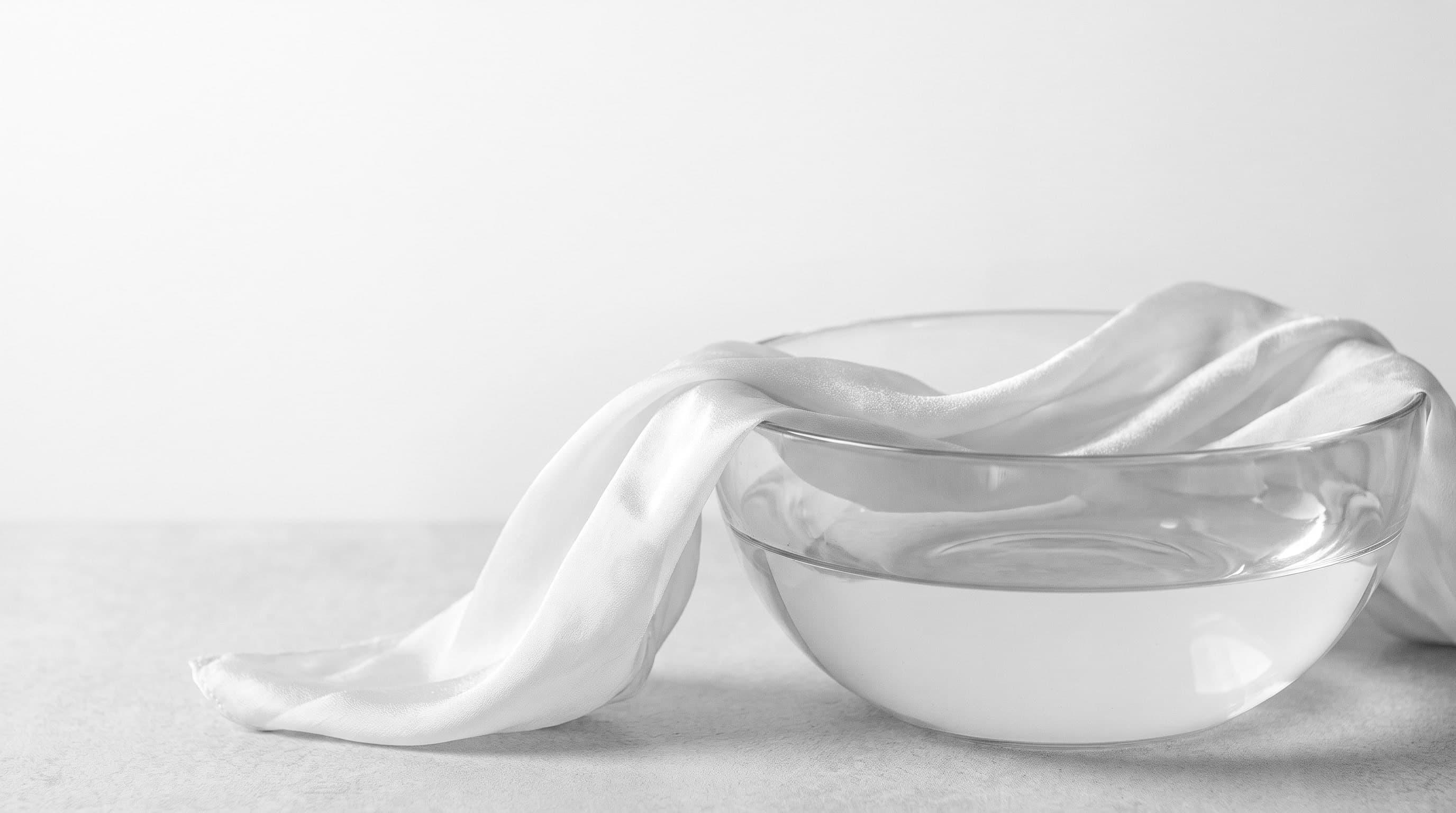 Weisse Seide über einer Glasschale mit stillem Wasser im weichen Tageslicht (Beispielbild)
